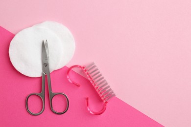 Photo of Pedicure procedure. Scissors, brush and cotton pads on pink background, flat lay. Space for text