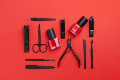 Photo of Set of pedicure tools on red background, flat lay