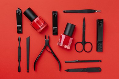 Photo of Set of pedicure tools on red background, flat lay