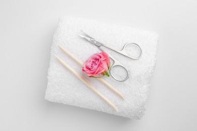 Photo of Pedicure procedure. Towel with scissors, orange sticks and flower on light background, top view