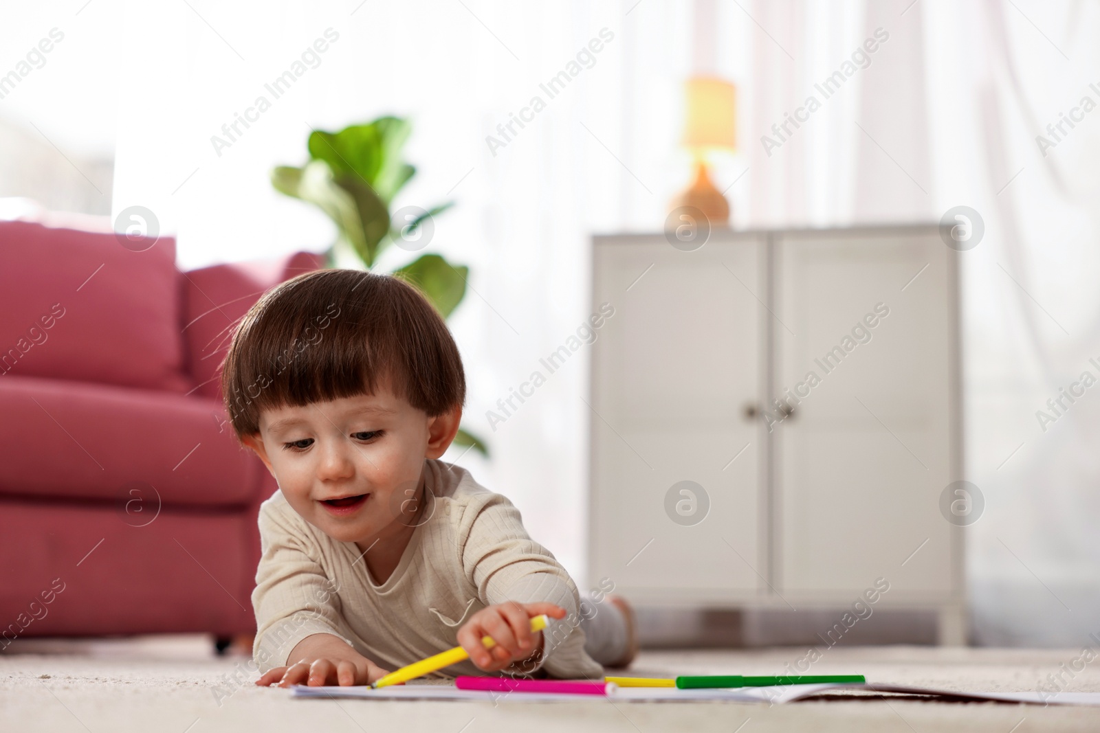 Photo of Cute little boy drawing on floor at home, space for text