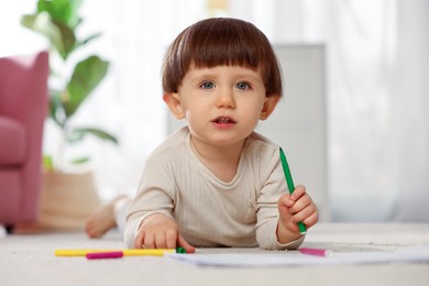 Photo of Cute little boy drawing on floor at home