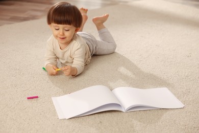 Photo of Cute little boy felt pen and sketchbook on floor at home, space for text