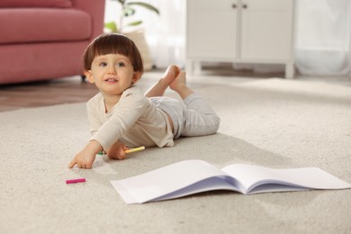 Photo of Cute little boy felt pen and sketchbook on floor at home, space for text