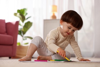 Photo of Cute little boy drawing on floor at home