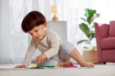 Photo of Cute little boy drawing on floor at home