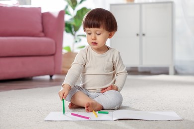 Photo of Cute little boy drawing on floor at home