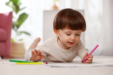 Photo of Cute little boy drawing on floor at home