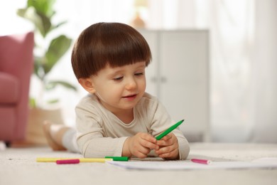 Photo of Cute little boy drawing on floor at home