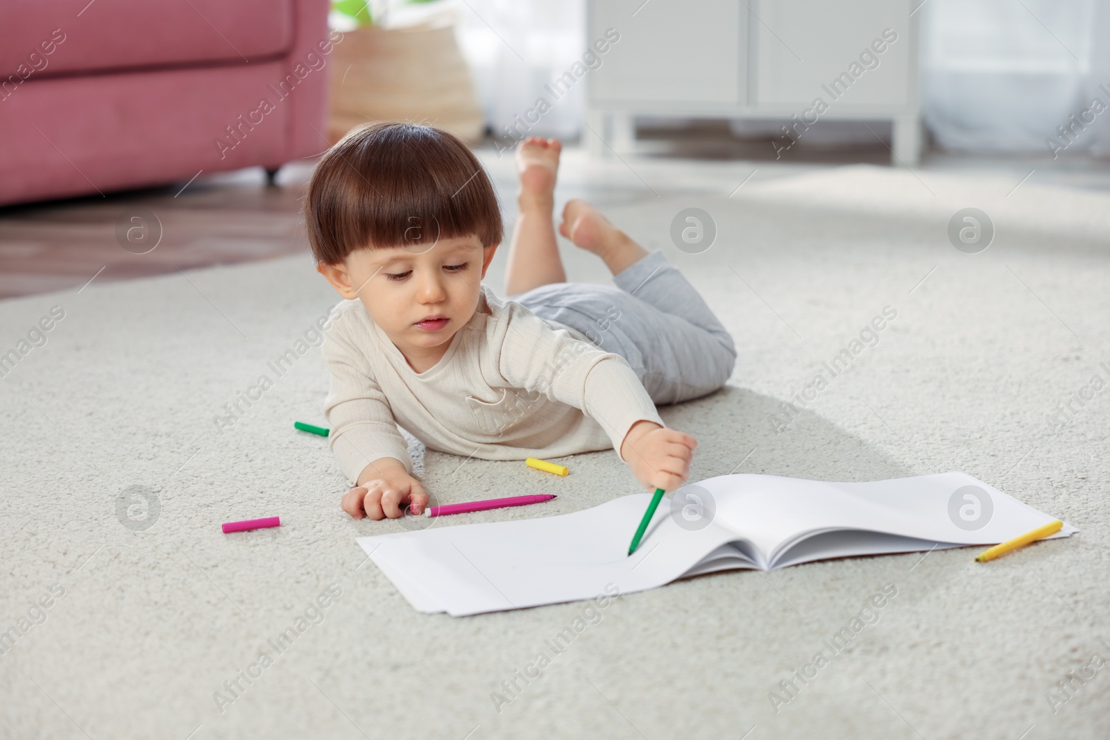 Photo of Cute little boy drawing on floor at home