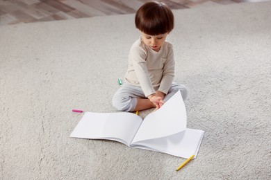 Photo of Cute little boy drawing on floor at home