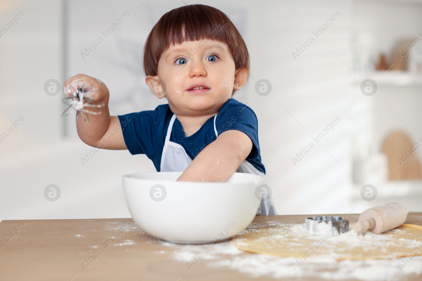 Photo of Cute little boy making dough at table indoors