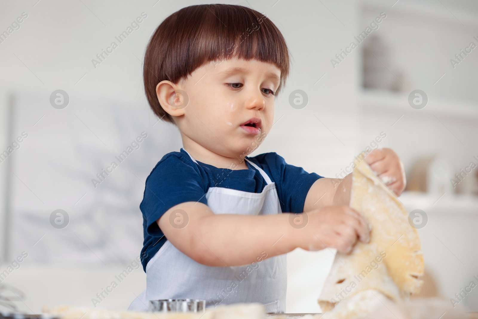 Photo of Cute little boy kneading dough at home