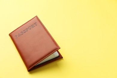 Photo of Passport in bright cover on yellow background, closeup. Space for text