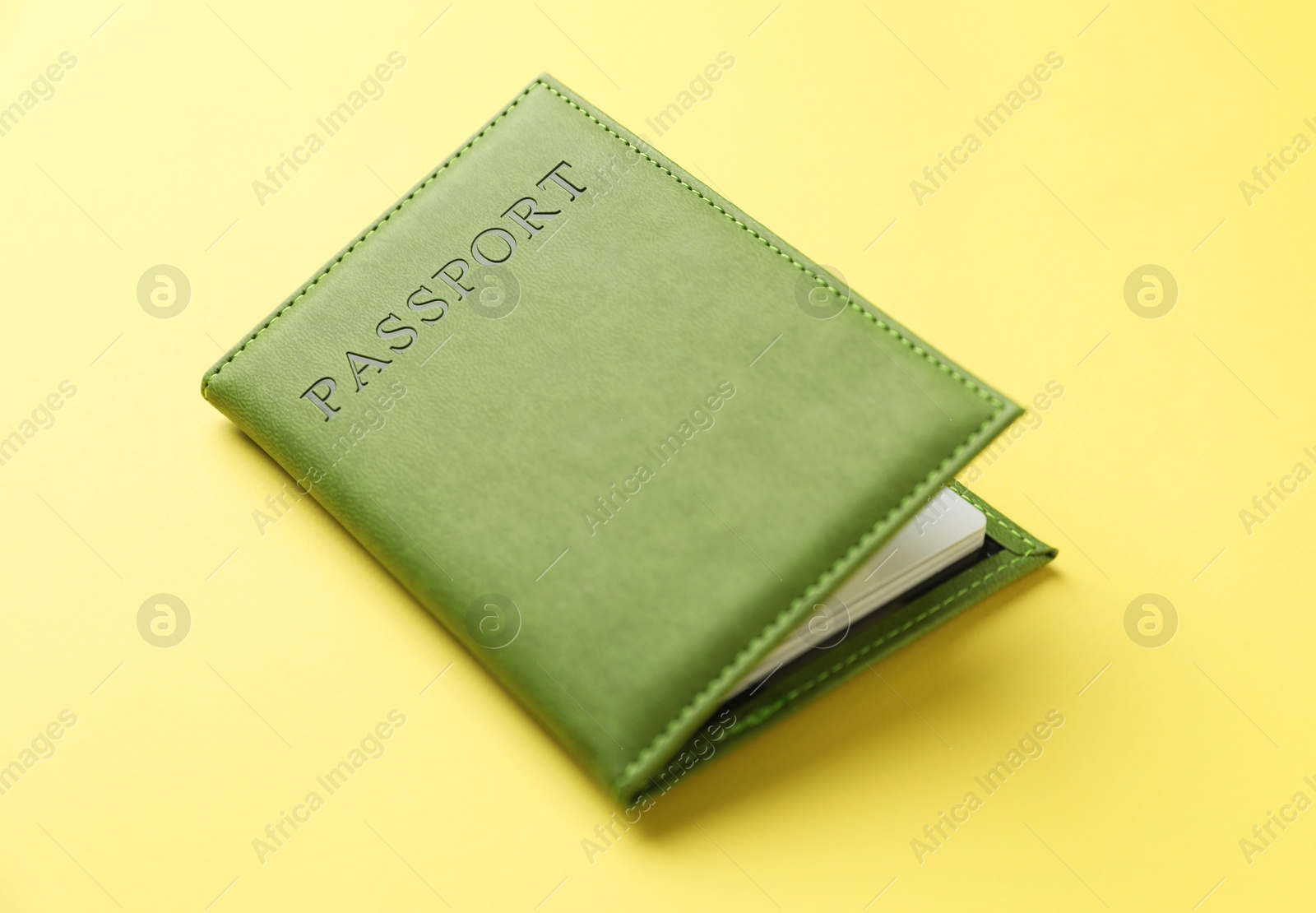 Photo of Passport in bright cover on yellow background, closeup