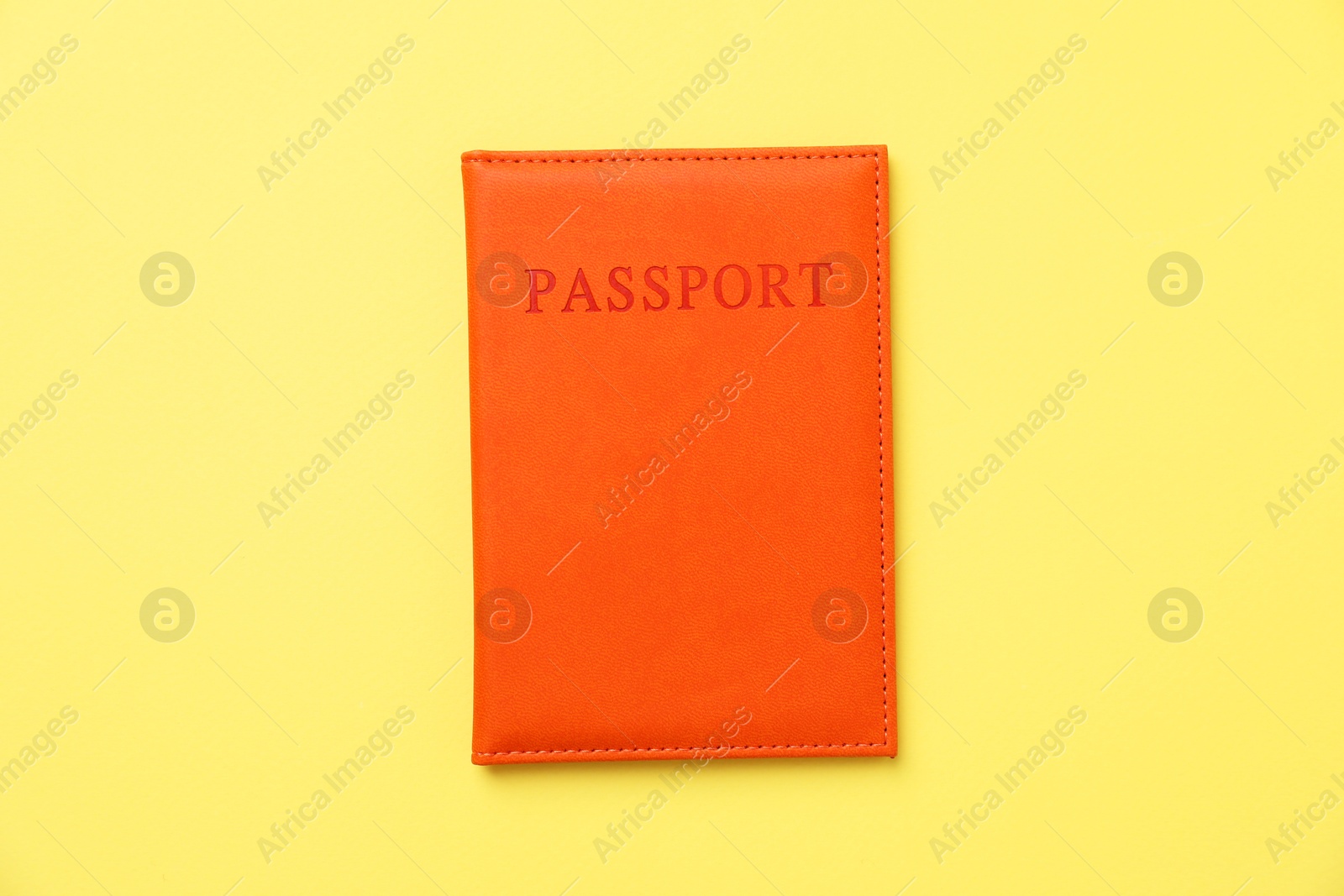 Photo of Passport in bright cover on yellow background, top view