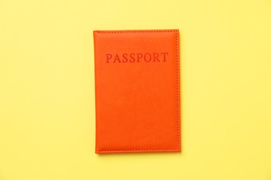 Photo of Passport in bright cover on yellow background, top view