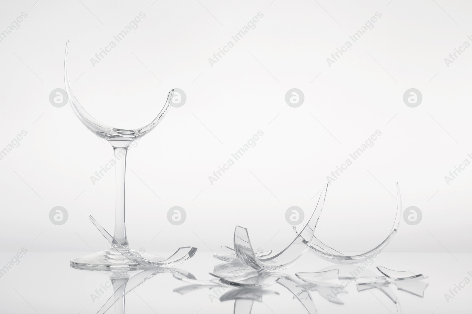 Photo of Pieces of broken wine glass on white background