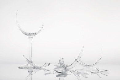 Photo of Pieces of broken wine glass on white background