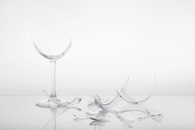 Photo of Pieces of broken wine glass on white background