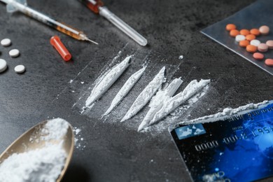 Photo of Drug addiction. Powder, syringes, credit card, spoon and pills on gray textured table, closeup