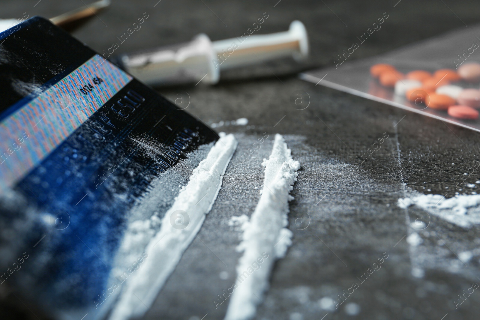 Photo of Drug addiction. Powder and credit card on gray textured table, closeup