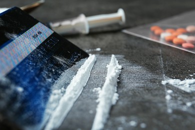 Photo of Drug addiction. Powder and credit card on gray textured table, closeup