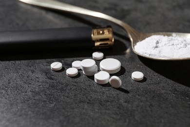 Photo of Drug addiction. Spoon with powder, pills and cigarette lighter on gray textured table, closeup