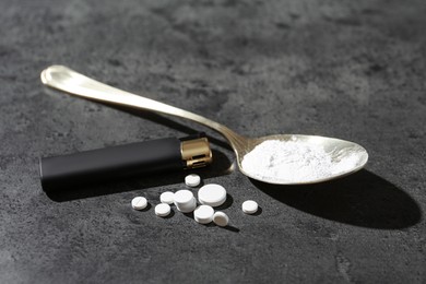 Photo of Drug addiction. Spoon with powder, pills and cigarette lighter on gray textured table