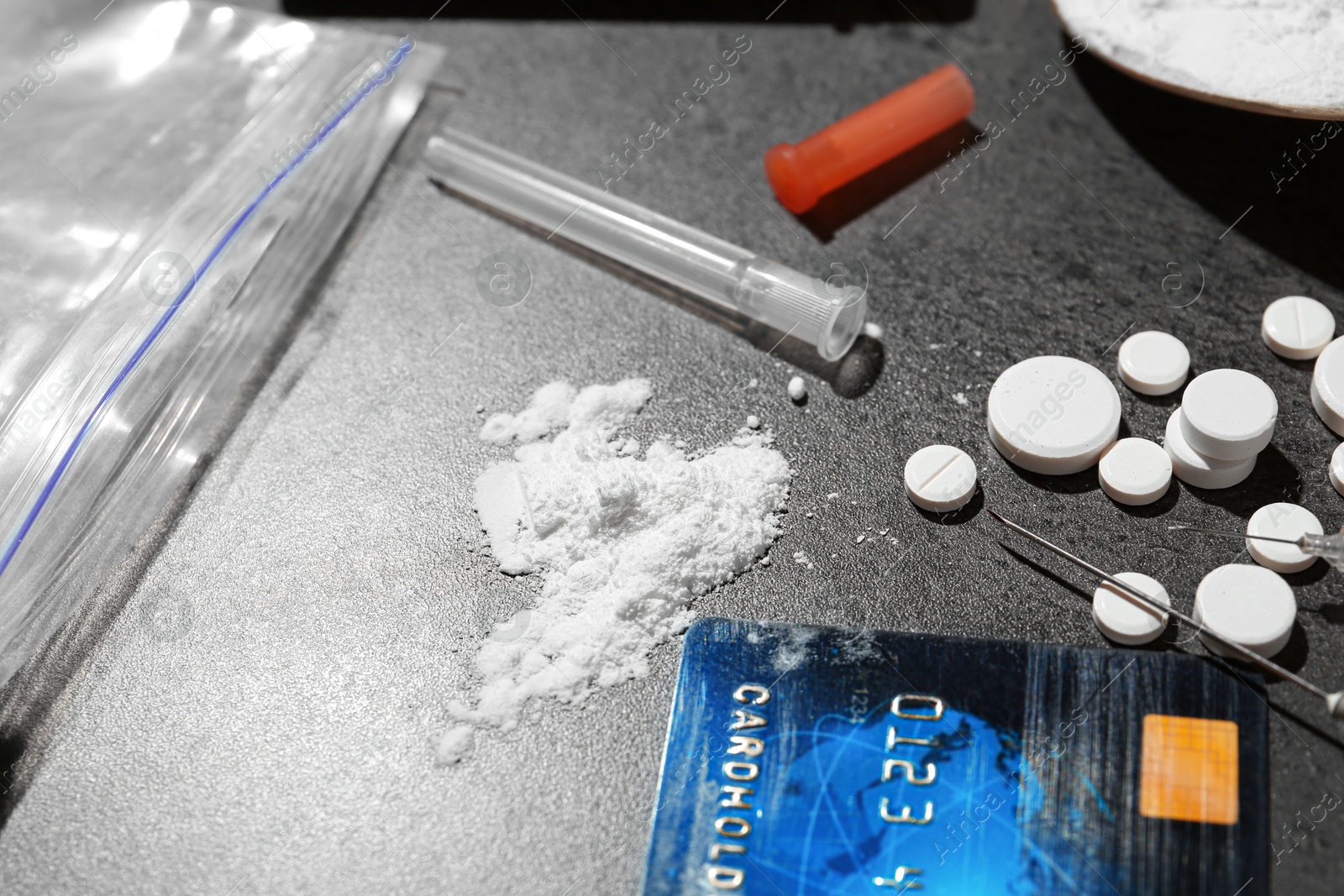 Photo of Drug addiction. Powder, pills, credit card and syringes on gray textured table, closeup