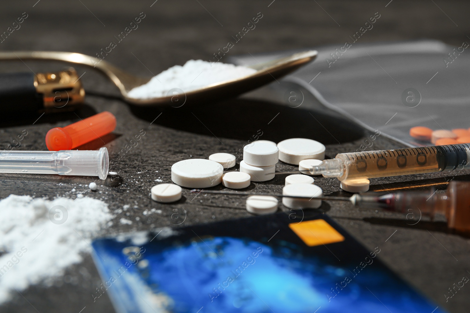 Photo of Drug addiction. Pills, syringes, credit card and spoon with powder on gray textured table, closeup