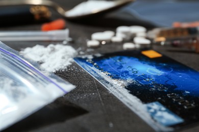 Photo of Drug addiction. Plastic bag with powder and credit card on gray textured table, closeup