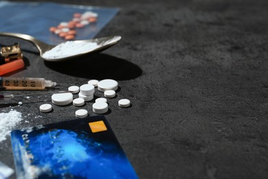 Photo of Drug addiction. Pills, syringes, credit card and spoon with powder on gray textured table, closeup. Space for text