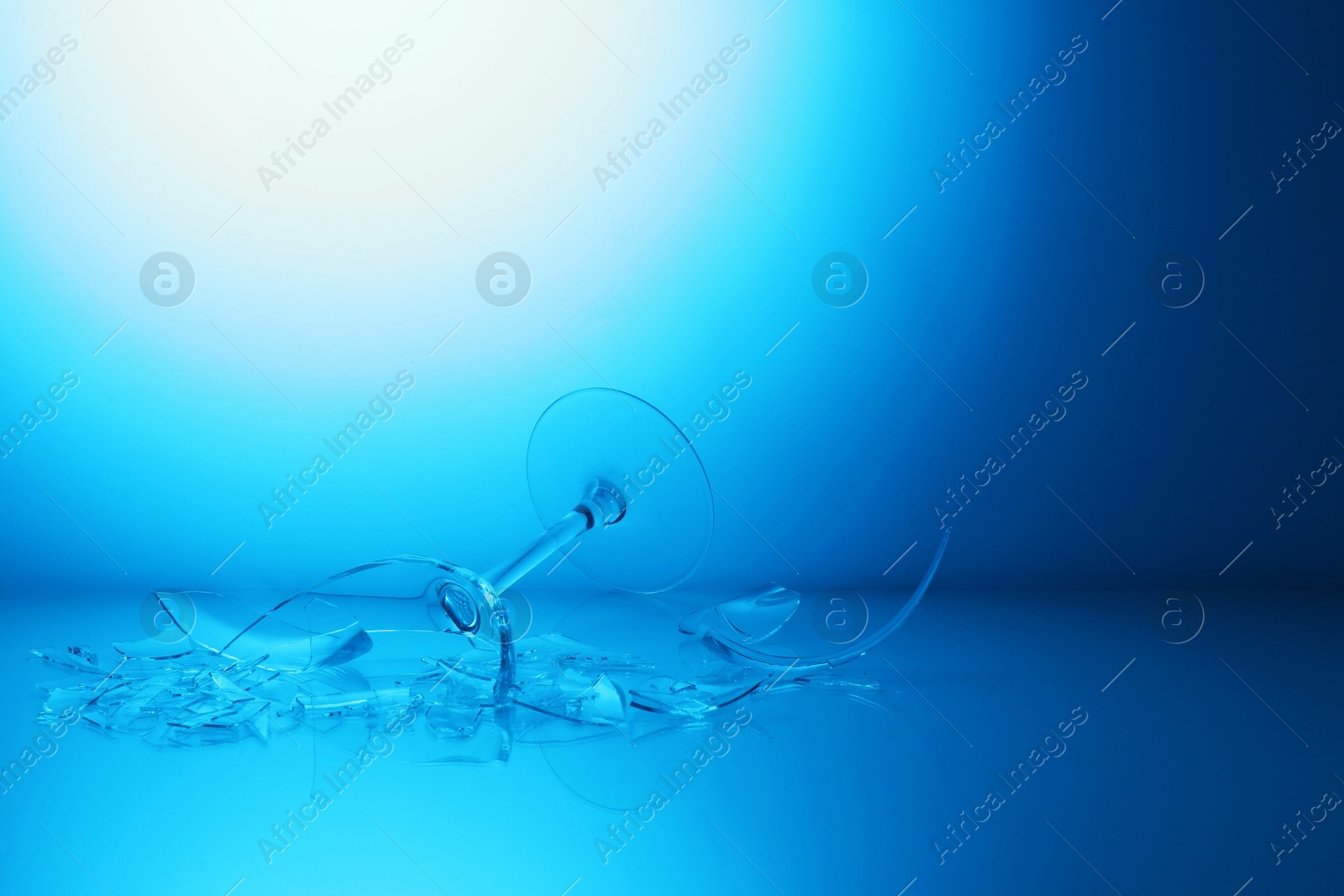 Photo of Pieces of broken wine glass against light blue gradient background, space for text