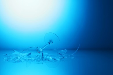 Photo of Pieces of broken wine glass against light blue gradient background, space for text