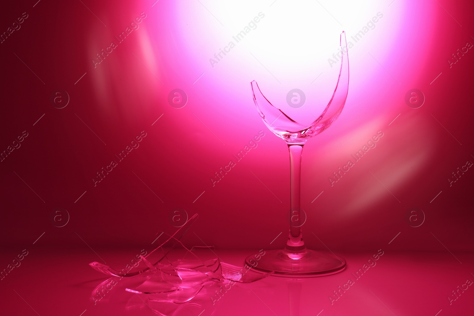 Photo of Pieces of broken wine glass against deep pink gradient background, space for text. Color tone effect