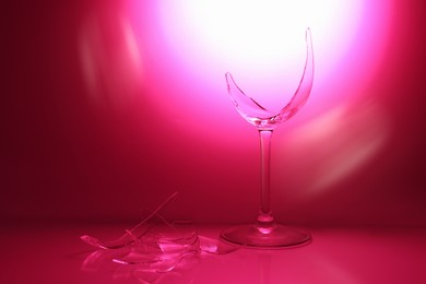 Photo of Pieces of broken wine glass against deep pink gradient background, space for text. Color tone effect