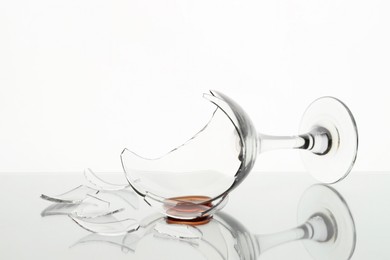 Photo of Pieces of broken glass with wine on table against white background, closeup