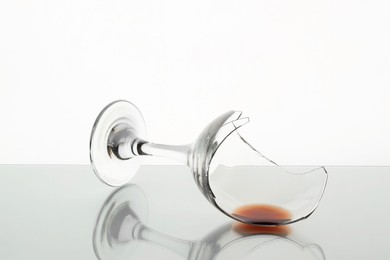 Photo of Piece of broken glass with wine on table against white background, closeup