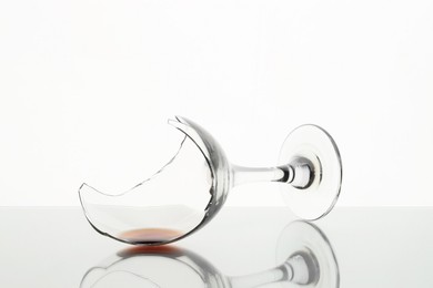 Photo of Broken glass with wine on table against white background, closeup