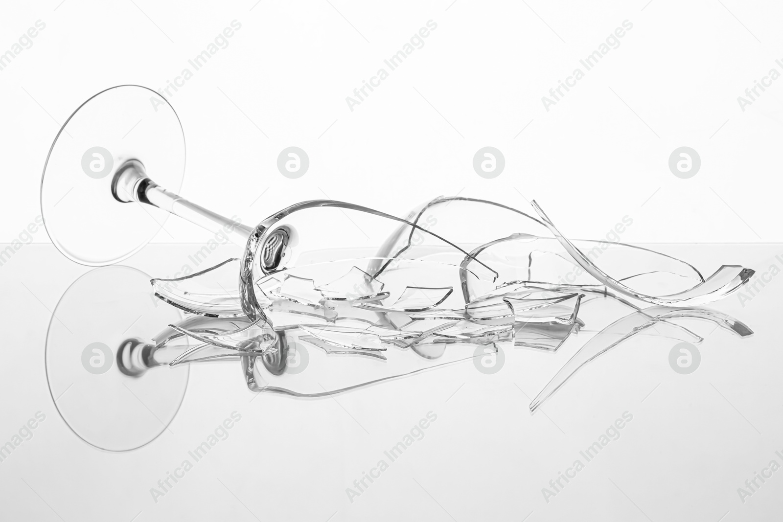 Photo of Pieces of broken wine glass on table against white background