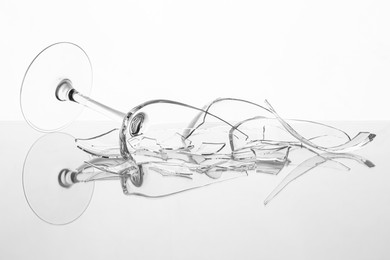 Photo of Pieces of broken wine glass on table against white background