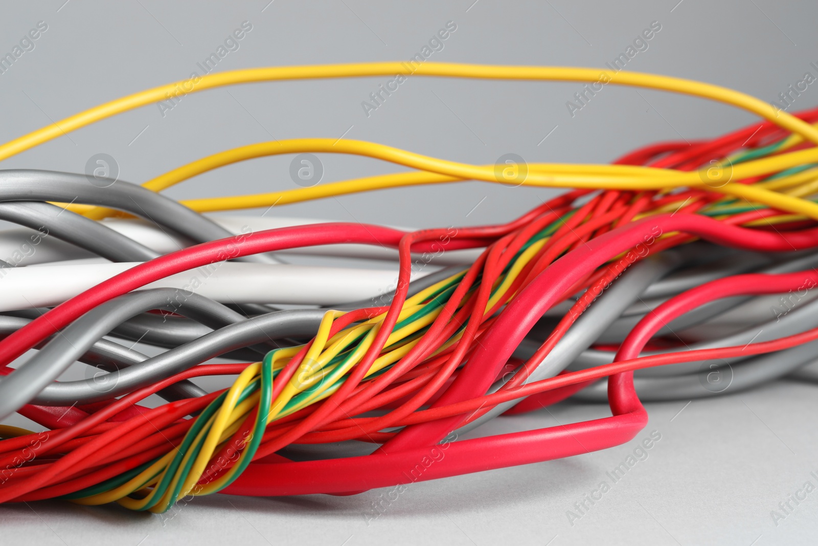 Photo of Many electrical wires on light grey background, closeup