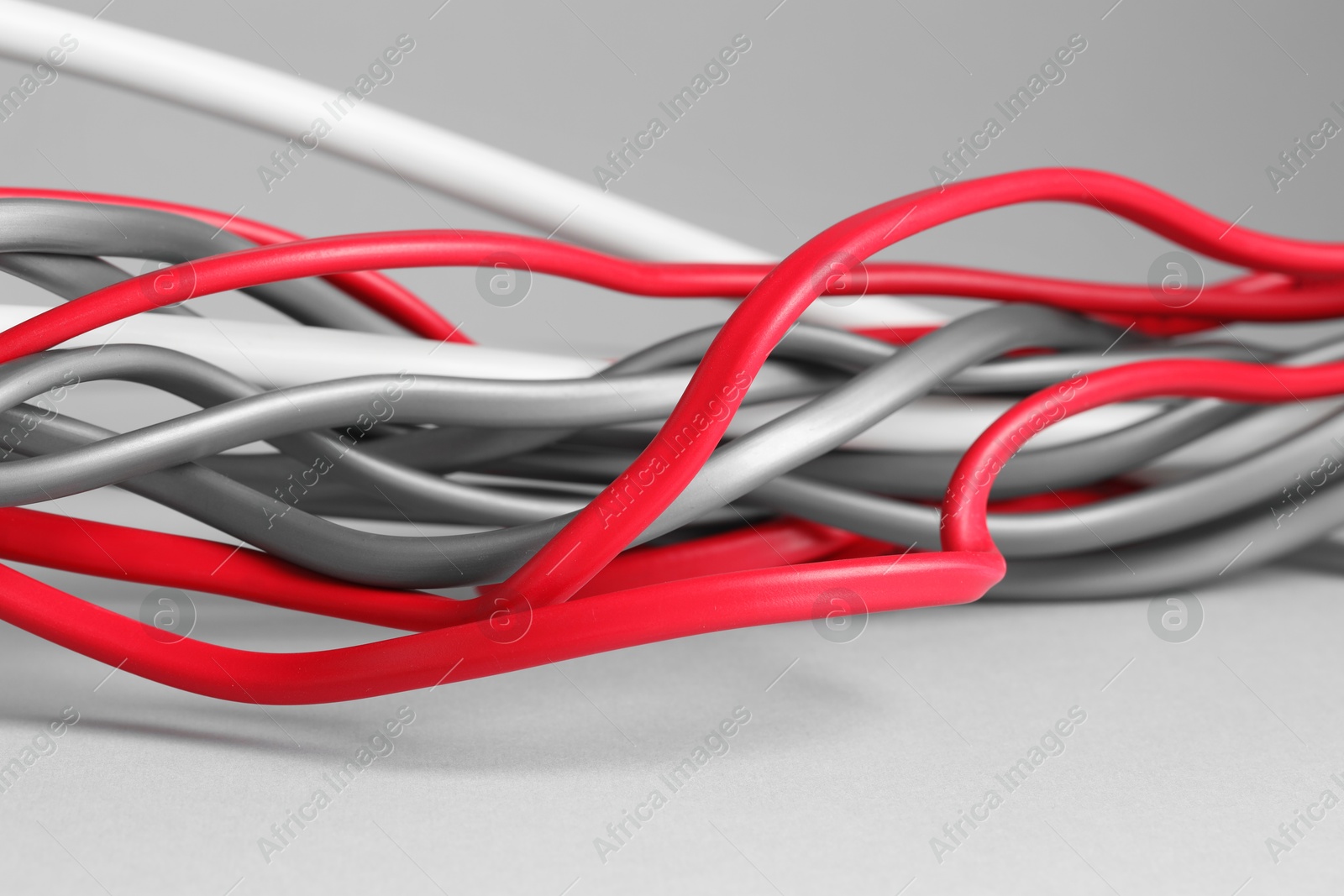 Photo of Many electrical wires on light grey background, closeup