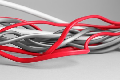 Photo of Many electrical wires on light grey background, closeup