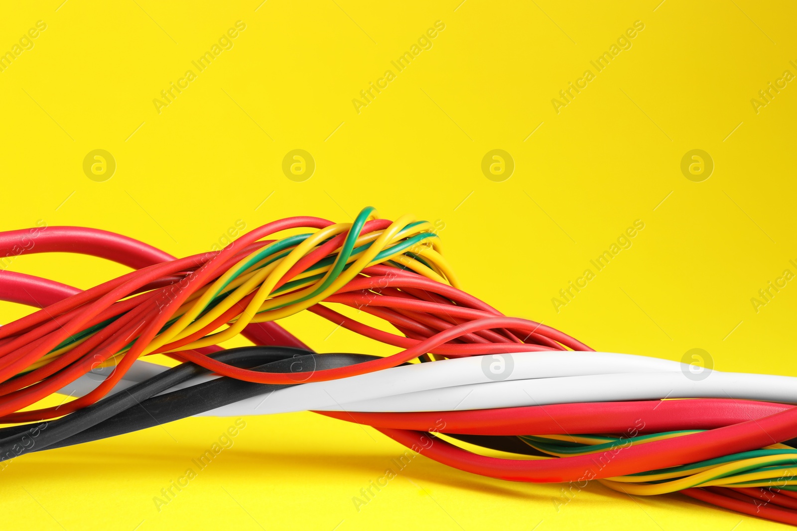 Photo of Many electrical wires on yellow background, closeup