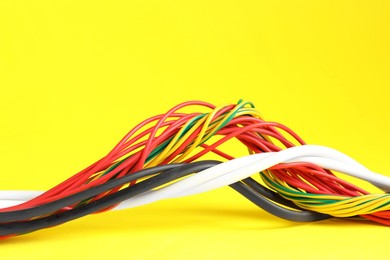 Photo of Many electrical wires on yellow background, closeup