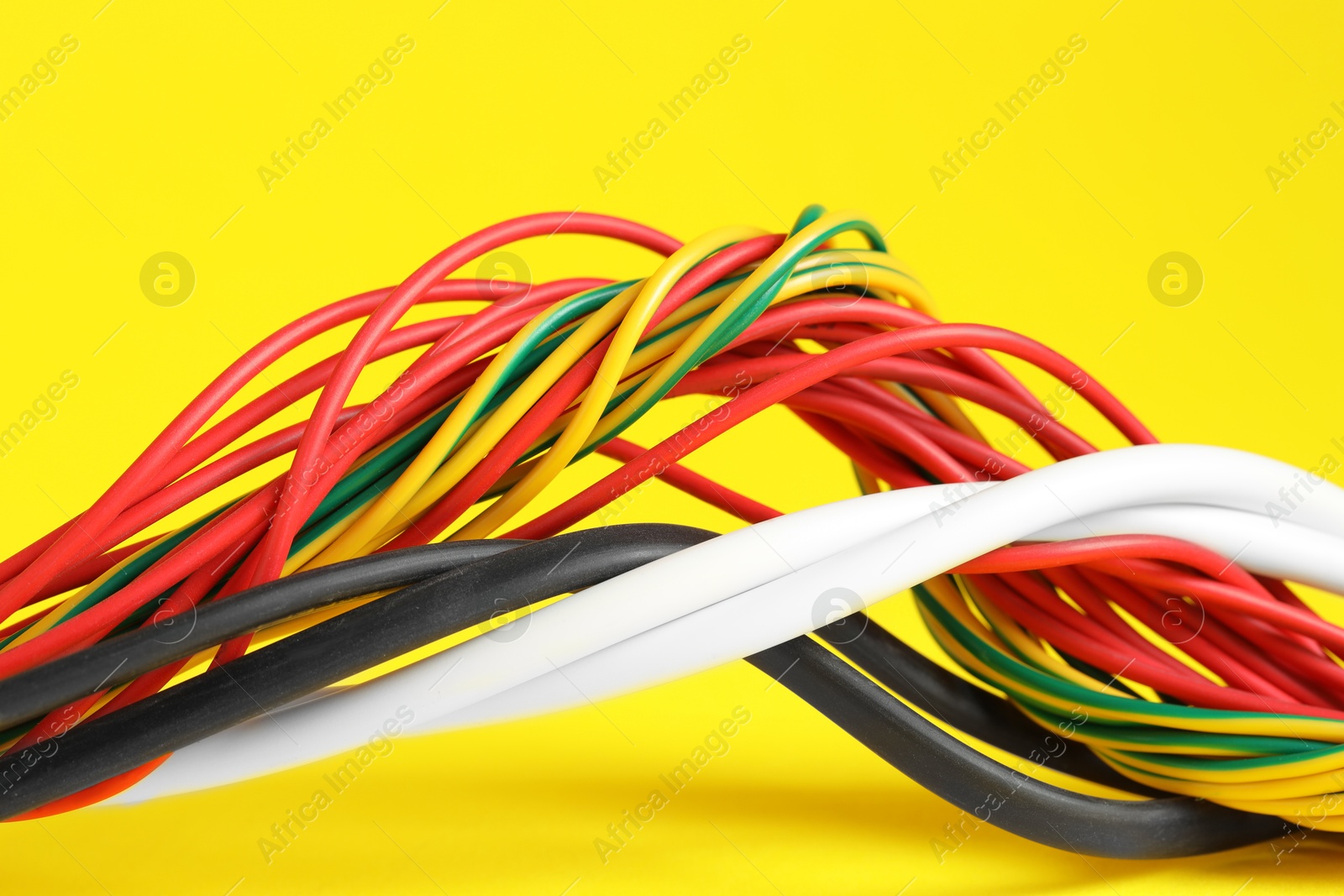 Photo of Many electrical wires on yellow background, closeup