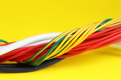 Photo of Many electrical wires on yellow background, closeup