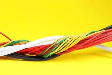 Photo of Many electrical wires on yellow background, closeup